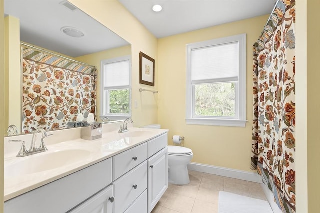 full bathroom featuring healthy amount of natural light, toilet, baseboards, and double vanity