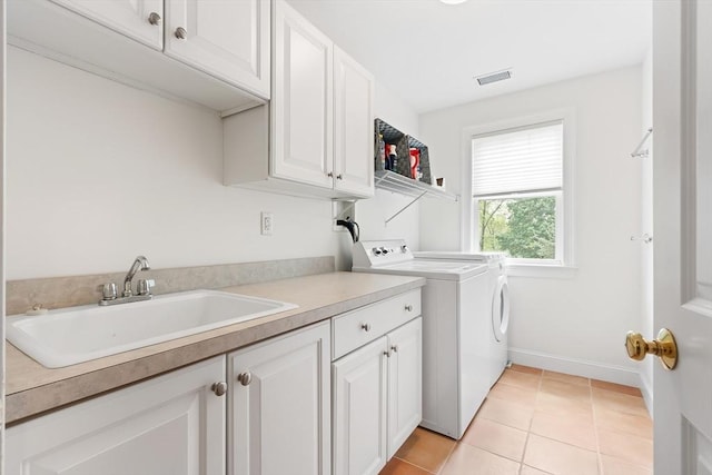 clothes washing area featuring washing machine and dryer, cabinet space, light tile patterned flooring, and baseboards