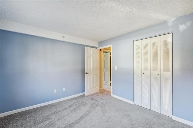 unfurnished bedroom featuring a textured ceiling, light colored carpet, and a closet