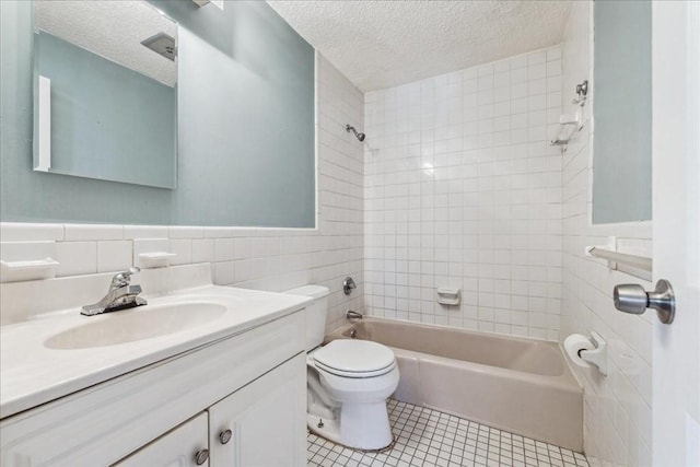 full bathroom with vanity, a textured ceiling, tile walls, toilet, and tiled shower / bath