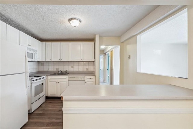 kitchen featuring decorative backsplash, dark hardwood / wood-style flooring, white appliances, sink, and white cabinets