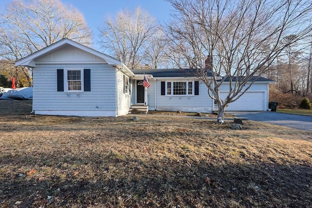 view of front of property with an attached garage, driveway, and a chimney