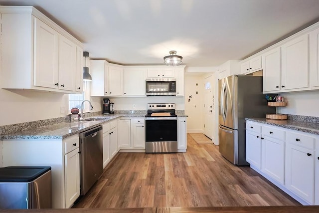 kitchen with a sink, stainless steel appliances, wood finished floors, and white cabinets