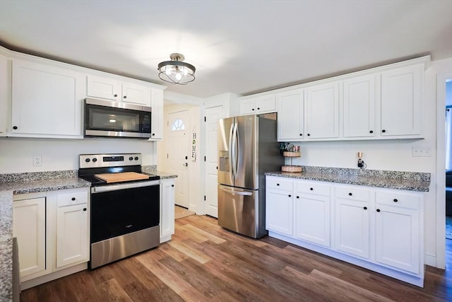 kitchen featuring dark wood finished floors, appliances with stainless steel finishes, white cabinetry, and light stone counters