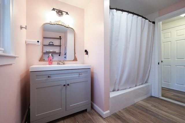 bathroom with baseboards, shower / tub combo, wood finished floors, and vanity