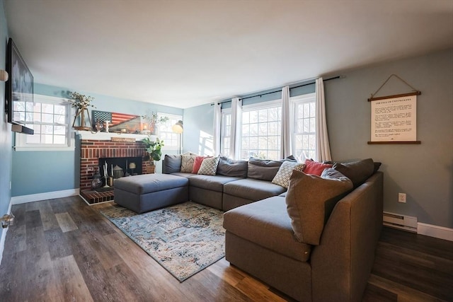 living area featuring a baseboard heating unit, baseboards, a brick fireplace, and wood finished floors