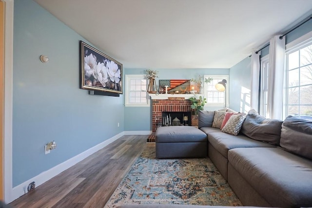 living area featuring baseboards, wood finished floors, and a fireplace