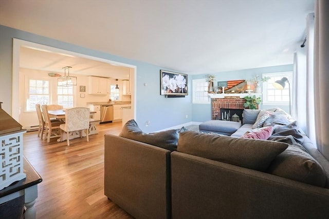 living area with light wood finished floors, a healthy amount of sunlight, a fireplace, and baseboards