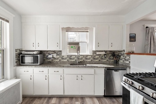 33 Alden Ave, Revere, MA 02151 - kitchen featuring stainless steel appliances, radiator, white cabinets, backsplash, and a sink