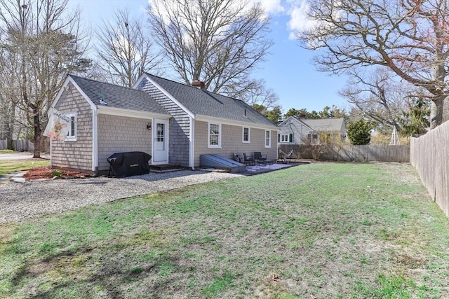 16 Samoset Rd, Yarmouth, MA 02664 - rear view of property featuring a fenced backyard, a shingled roof, a lawn, and a chimney