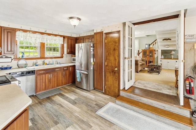 650 Pearse Rd, Swansea, MA 02777 - kitchen with stainless steel appliances, a sink, light countertops, light wood-type flooring, and brown cabinetry