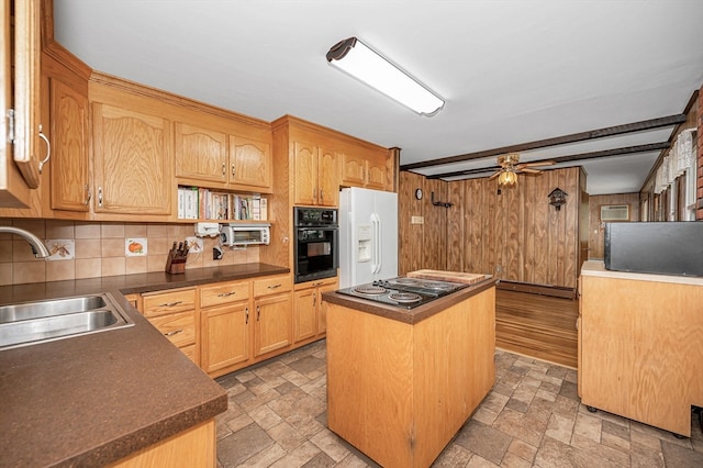 kitchen featuring stainless steel gas cooktop, white fridge with ice dispenser, black oven, sink, and a center island