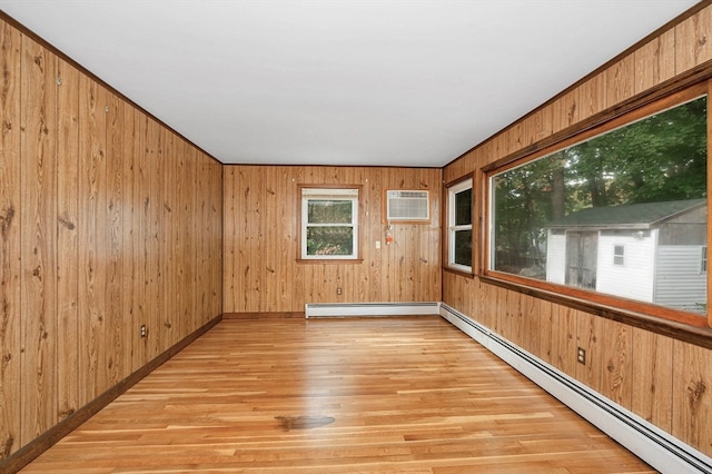 unfurnished room with a wall unit AC, light hardwood / wood-style flooring, wood walls, and a baseboard heating unit