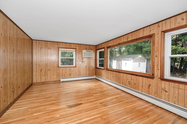 spare room featuring light hardwood / wood-style flooring, wood walls, baseboard heating, and plenty of natural light