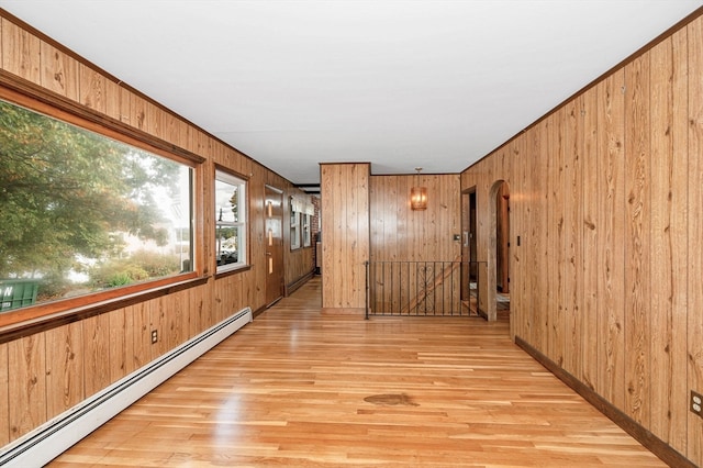 hall featuring a baseboard radiator, light wood-type flooring, and wood walls