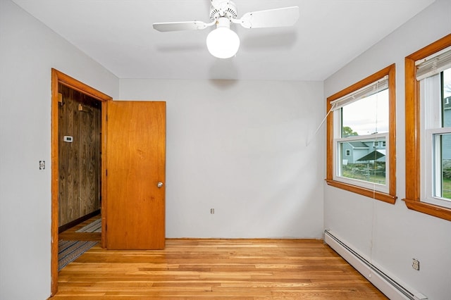 unfurnished room with light hardwood / wood-style flooring, a baseboard radiator, plenty of natural light, and ceiling fan