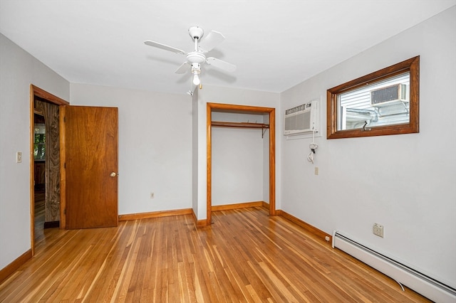 unfurnished bedroom featuring a closet, light wood-type flooring, baseboard heating, and a wall unit AC