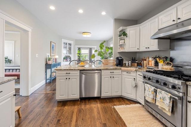 kitchen featuring appliances with stainless steel finishes, under cabinet range hood, a peninsula, white cabinets, and a sink