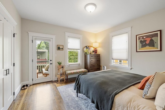 bedroom featuring access to exterior, wood finished floors, and baseboards