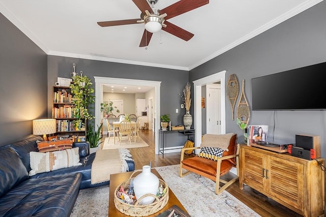 living area with wood finished floors, a ceiling fan, and ornamental molding