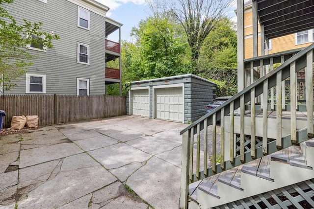view of patio / terrace featuring an outbuilding, fence, stairway, and a garage