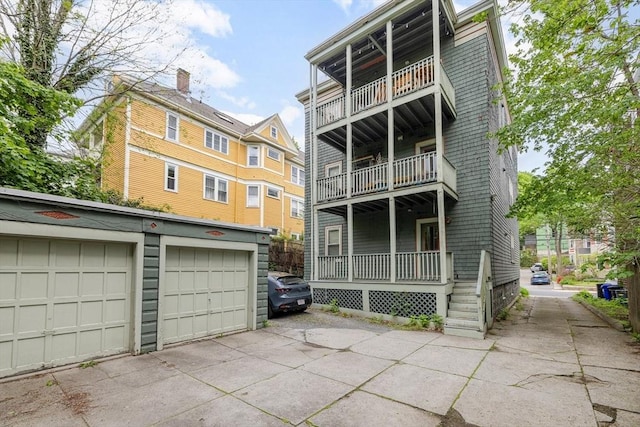 back of property featuring a balcony, an outdoor structure, and a garage