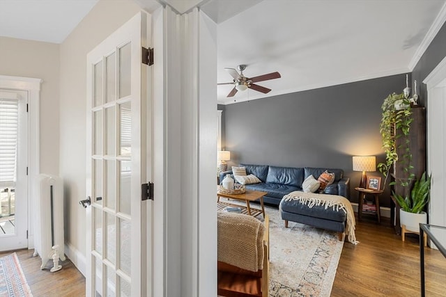 living area featuring a ceiling fan, wood finished floors, radiator heating unit, and ornamental molding