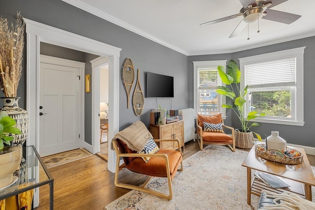 living area featuring wood finished floors, crown molding, and ceiling fan