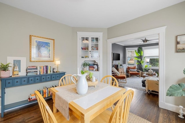 dining space featuring dark wood-type flooring, a ceiling fan, and baseboards