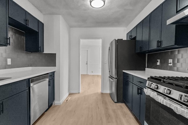 kitchen with light hardwood / wood-style flooring, ventilation hood, tasteful backsplash, and appliances with stainless steel finishes