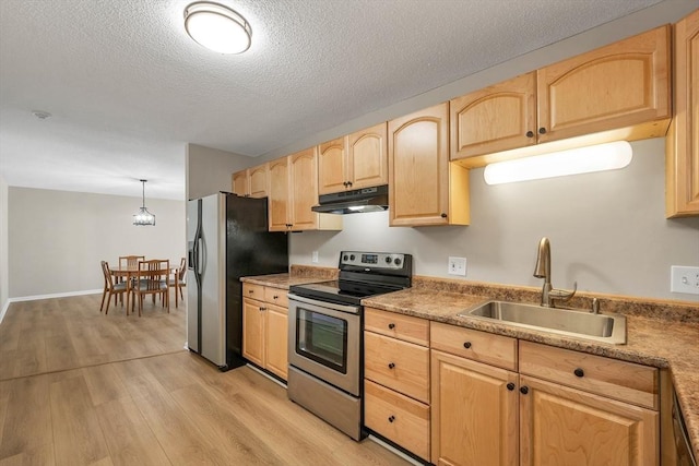 kitchen featuring under cabinet range hood, stainless steel appliances, a sink, hanging light fixtures, and light countertops