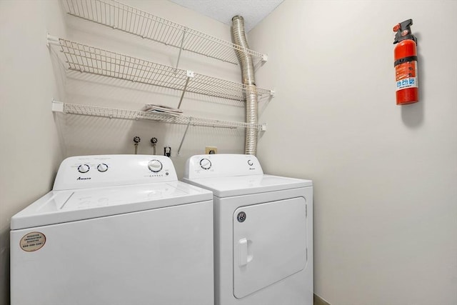 clothes washing area featuring a textured ceiling, laundry area, and independent washer and dryer