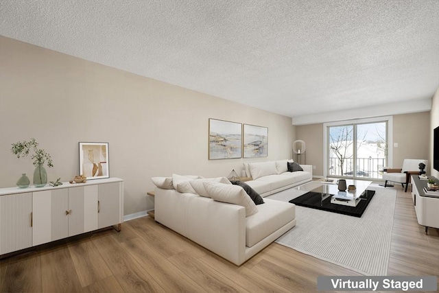 living room with light wood finished floors, baseboards, and a textured ceiling