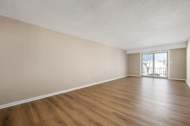 unfurnished room featuring light wood-style flooring, baseboards, and a textured ceiling