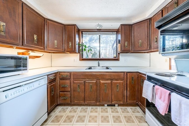 kitchen featuring white appliances, sink, and a textured ceiling