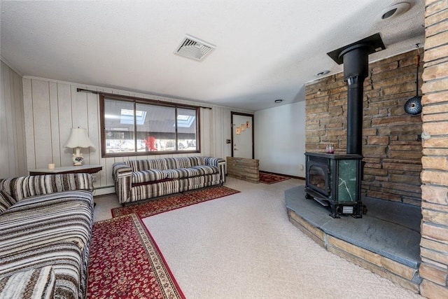 living room with a baseboard heating unit, carpet, and a wood stove