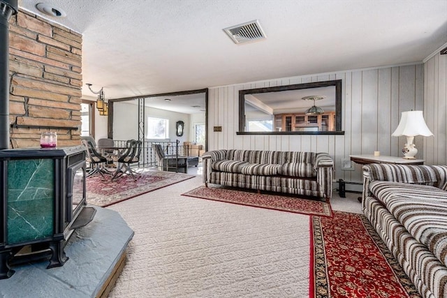 living room featuring wooden walls, a textured ceiling, and a wood stove