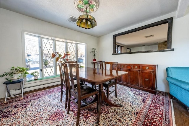 dining room featuring light parquet flooring, a baseboard heating unit, and a textured ceiling