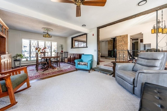 carpeted living room featuring a baseboard heating unit, beam ceiling, ceiling fan, and a wood stove