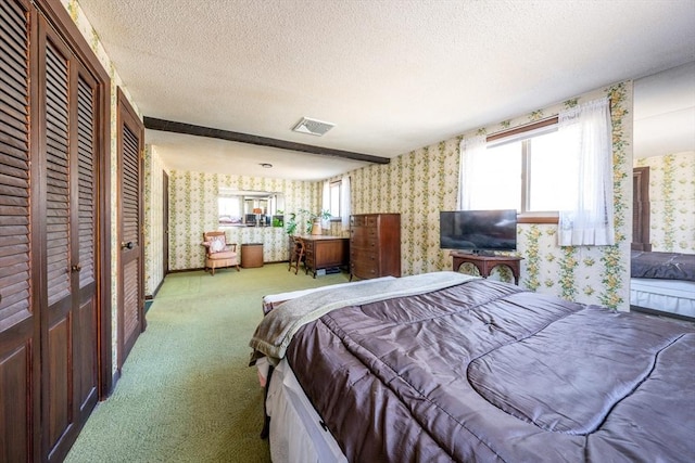 carpeted bedroom featuring multiple closets, a textured ceiling, and beamed ceiling