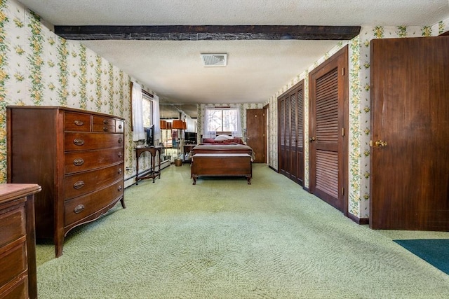 carpeted bedroom featuring beam ceiling and a textured ceiling