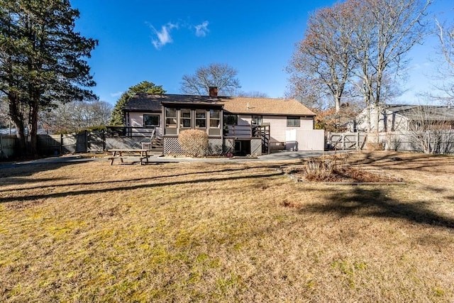 rear view of property featuring a yard, a sunroom, and a deck