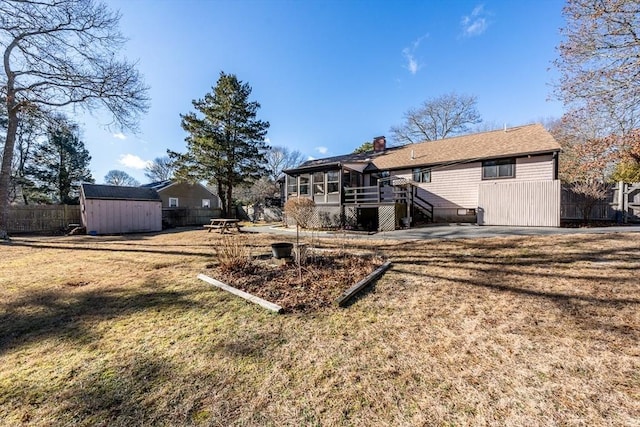 back of house with a storage unit, a sunroom, and a lawn