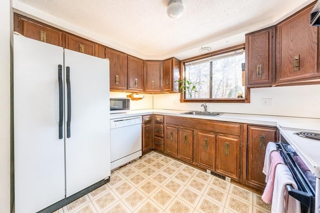 kitchen with sink, a textured ceiling, and white appliances