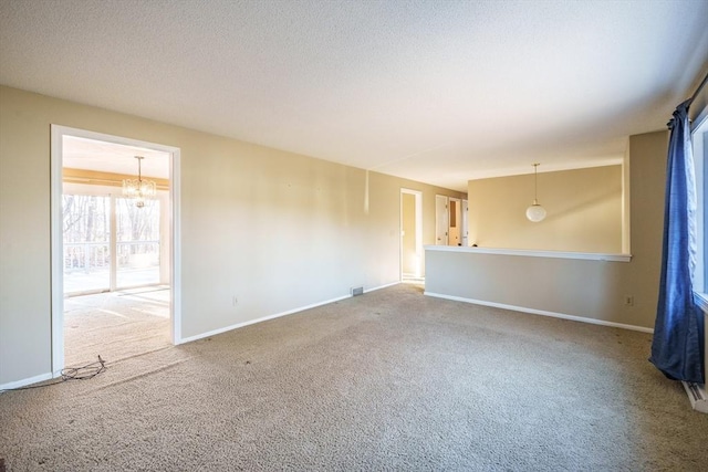 empty room with carpet flooring, baseboards, a chandelier, and a textured ceiling