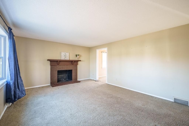 unfurnished living room featuring visible vents, a brick fireplace, baseboards, and carpet