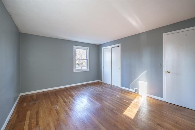 unfurnished bedroom featuring visible vents, baseboards, and wood finished floors