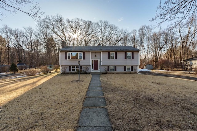 split foyer home with a front lawn and a chimney