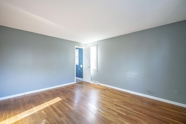 empty room with visible vents, baseboards, and hardwood / wood-style flooring