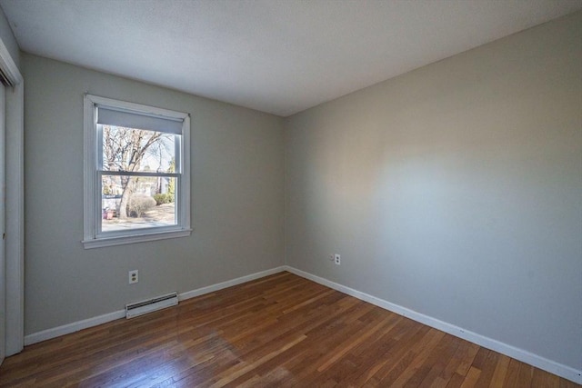 unfurnished room with wood finished floors, baseboards, and a baseboard radiator